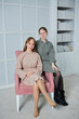 Two girlfriends of high school age in the interior are sitting on a pink armchair