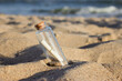 © Kira Ray - a message in a bottle is buried in the sand on the beach