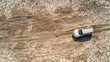 A white car is driving on a dirt road in the desert. Top view of an SUV driving along a dry road cracked due to drought