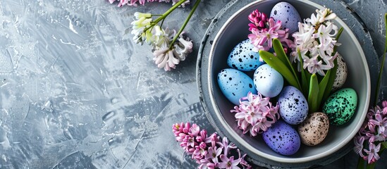 Above the spring table arrangement features hyacinth flowers and colorful eggs on a grey concrete table for a festive dinner.