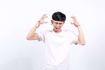 Stressed asian young boy with red white ribbon for celebrating Indonesia independence day standing while screaming