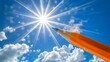 Pencil reaching for the sun in the blue sky with clouds. Concept of reaching goals, imagination, and creativity.