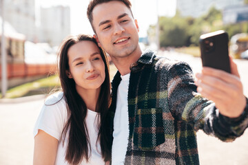 Wall Mural - Smiling beautiful woman and her handsome boyfriend. Woman in casual summer clothes. Happy cheerful family. Female having fun. Sexy couple posing in the street at sunny day, take selfie