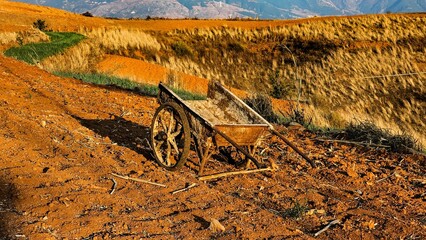 Antique cart rests on a dusty path with mountains in the background at Wa Fang Liang Zi China