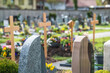 Grabsteine auf Friedhof mit unscharfen Holzkreuzen im Hintergrund