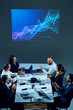 © master1305 - Colleagues in corporate setting analyze market data while examining a digital stock chart displayed on a monitor. Concept of business, entrepreneurship, trade market, economics, finances