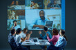 © master1305 - Workers seated at a table in the boardroom participate in virtual meeting, having online corporate English lesson with tutor. Concept of business, entrepreneurship, communication, teamwork