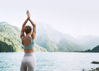 Wall Mural - Young woman is practicing yoga at mountain lake.