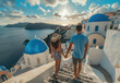 Young couple in love walking along the stairs of Oia, Santorini island with blue domes and white church buildings on Greek volcano landscape