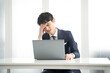 ノートパソコン作業中に頭痛を訴える男性ビジネスマン
