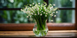 Lily of the Valley in a Glass Vase on Wooden Table. A glass vase filled with delicate white lily of the valley flowers sits on a rustic wooden table. The lily of the valley has bell-shaped white flowe