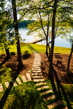 A Path Leading From A Back Porch To Sparkling Water On A Lake In The Morning
