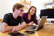 © Austockphoto - Caucasian man and Aboriginal woman sitting together at a table in an office looking at a laptop