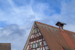 Detail Giebelseite Fachwerkhaus mit Sprossenfenstern, Fensterladen und Glockenturm vor blauem Himmel mit Wolken