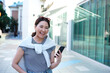 © Austockphoto - Portrait of woman laughing and holding mobile phone on urban footpath