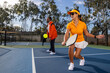 © Mat Hayward - Mixed race couple playing a game of pickleball together outside on a court.