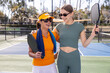 © Mat Hayward - Two women standing together on a pickleball court outside.