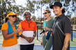 © Mat Hayward - Group of four happy pickleball players talk and laugh together outside on a court.
