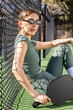 © Mat Hayward - Female pickleball player wearing a green body suit sits on the court between games. The woman is wearing sunglasses and is sitting comfortably with a paddle and a ball.