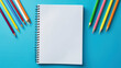 top view of blank notebook and colorful pencils on blue background. school desk with stationery. background for education concept