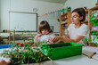 Young female teacher with boy taking care of potted plant in kindergarten