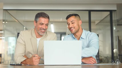 Wall Mural - Two busy happy business men partners working together talking using laptop in office. Male manager and employee looking at computer discussing investment business project at office meeting.