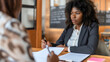 © Nemanja - African American businesswoman doing the paperwork on an office desk or table, holding a pen. Signing, reading contract document, female employee at job workplace workspace