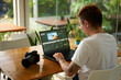 Pro videographer edits wildlife footage on laptop in a bright office. Color grading process by creative with camera gear beside. Concentrated freelancer tweaks travel video in a workspace.