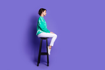 Wall Mural - Full size photo of attractive young woman profile sit chair dressed stylish green clothes isolated on violet color background