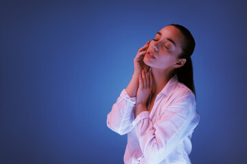 Wall Mural - Portrait of beautiful young woman posing on blue background with neon lights, space for text