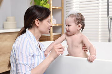 Sticker - Mother bathing her cute little baby in tub at home