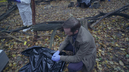 Detective reaches the crime scene where a murder victim lies in a body bag, ready for forensic examination 