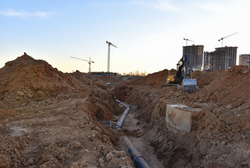 Wall Mural - `Storm sewer pipes laying. Sanitary drainage, external sewage. Tower crane on building construction. Excavator dig trench on construction site. Stormwater dig, sewer pipe. Sewer construction, Sewerage