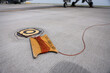 Electrical grounding cables are seen on a runway. Military fighter aircraft in the background.