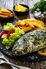 Wall Mural - Grilled sea bream, French fries and fresh vegetables on wooden table