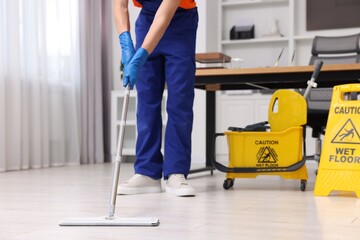 Poster - Cleaning service worker washing floor with mop, closeup. Bucket with wet floor sign in office