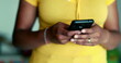 One young black woman using cellphone device standing up. African American 20s person holding phone engaged with modern technology