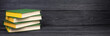 Books on wooden table, black board background. Back to school. Education business concept. panorama, banner.
