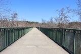 Fototapeta Niebo - The long pathway bridge in the park on a sunny day.