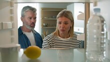 Adult Middle-aged Family Couple Woman Man Mature Husband Wife POV Point Of View From Inside Fridge Open Empty Refrigerator With Water And Lemon Conflict Furious Quarrel Angry Argue Problem Dispute