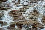 Fototapeta Las - Water from the small mountain creek flows over the rocks.