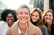 Portrait group of multiracial empowered business women of diverse ages looking smiling at camera with happy and confident expression. Caucasian attractive woman with short hair standing in foreground