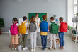 © Studio Romantic - Small group of children in casual clothes gets acquainted with smiling teacher of individual classes. Teenagers with backpacks on their backs lined up in front of their teacher in the classroom.