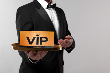 Wall Mural - Man holding tray with VIP sign on light grey background, closeup. Space for text