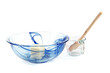 a blue glass mixing bowl with butter and an empty measuring cup isolated on white