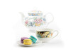 a plate of colorful macaroon or meringue cookies with a teacup and a teapot on a white background