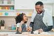 © chokniti - In a home kitchen, black father and his daughter bond over cooking a meal food, their laughter and love filling the air, embodying the joy of African American family life, Father's Day concept