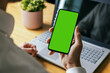 man holding mobile phone in hand with blank green screen. mockup template