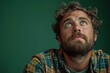 A serene portrait of a bearded man looking upwards with a hopeful, dreamy expression against a green background