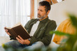© Nuria Seguí/Stocksy - Man Reading Book On Sofa